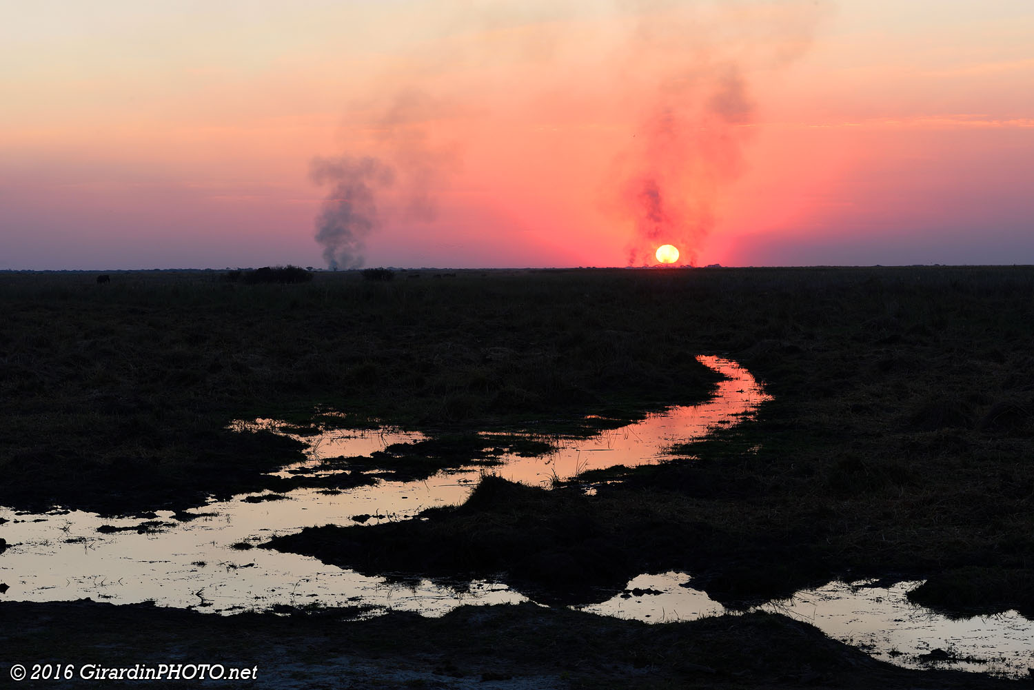 Coucher de soleil derrière des feux de brousse