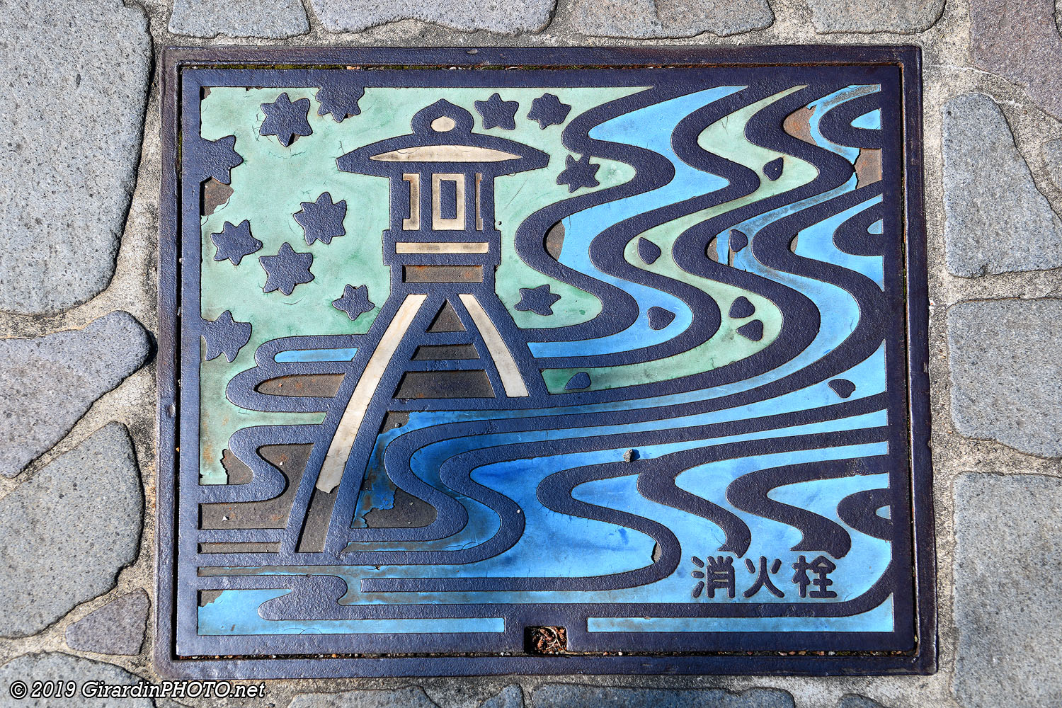 Grille d’égout avec la lanterne Kotojitoro du Kenroku-en Garden